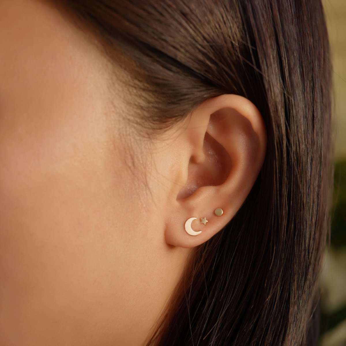 14K gold tiny disc stud worn in a model's upper lobe, shown close up