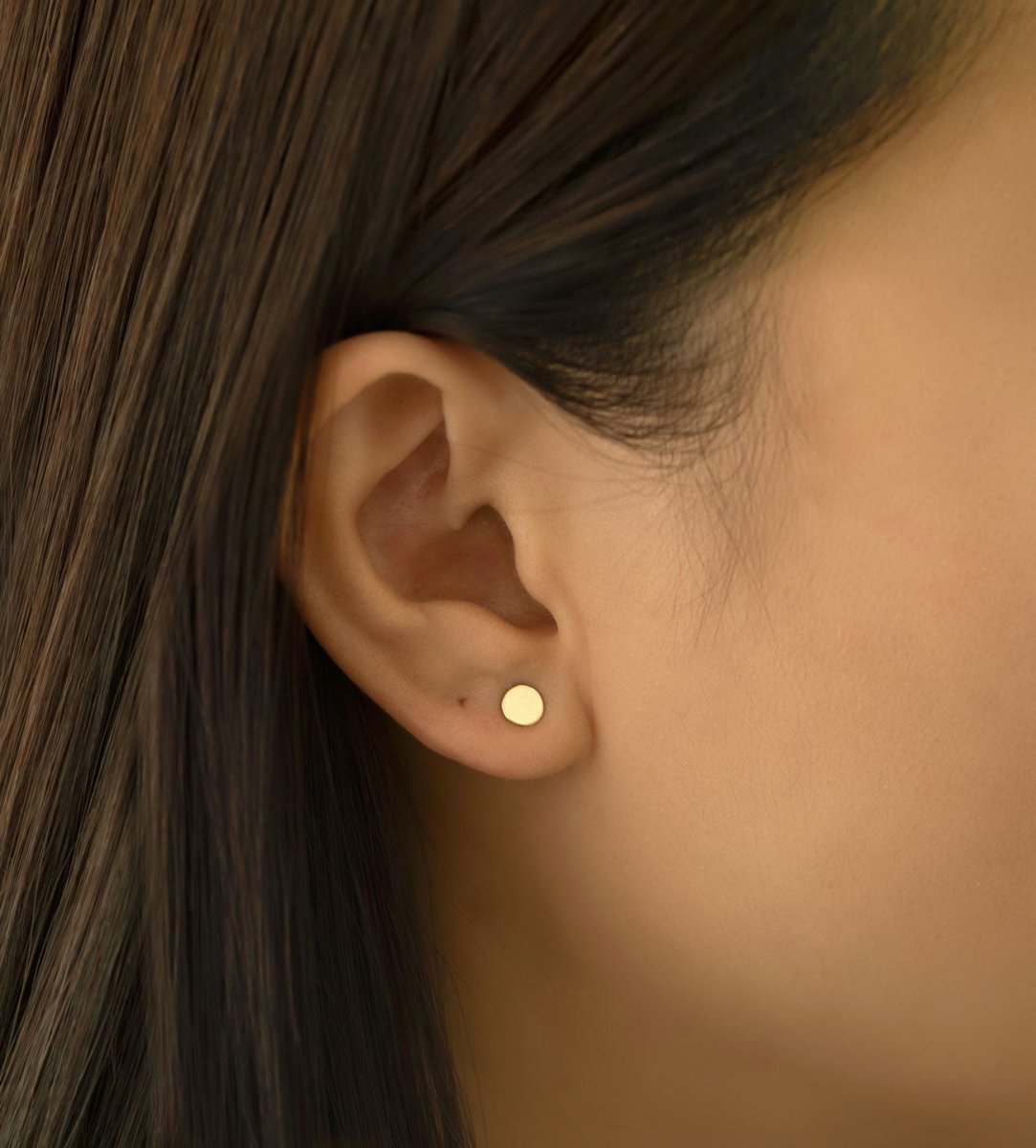 Gold vermeil flat round disc stud earring shown on a model's lobe, close-up detail