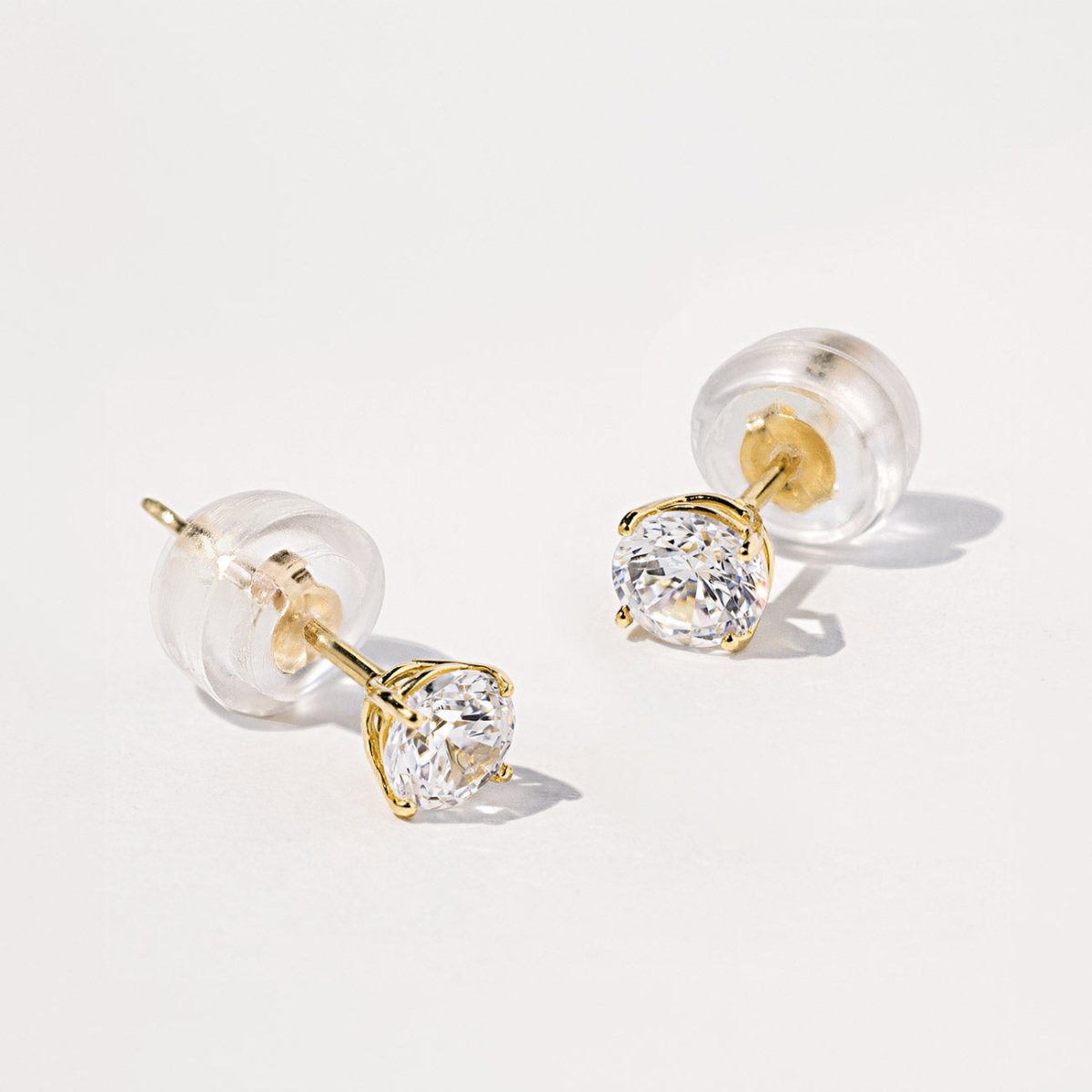 14K gold white sapphire stud with a silicone back, close-up detail on a white surface