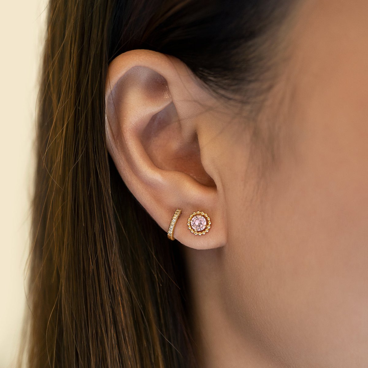 14K gold beaded-halo pink sapphire stud shown on a model's lobe with a pavé hoop