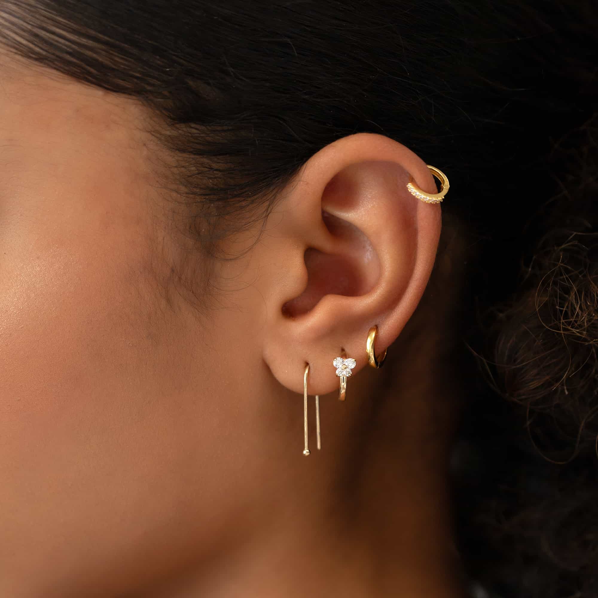 14K gold butterfly huggie hoop with white zirconia shown on a model's lobe