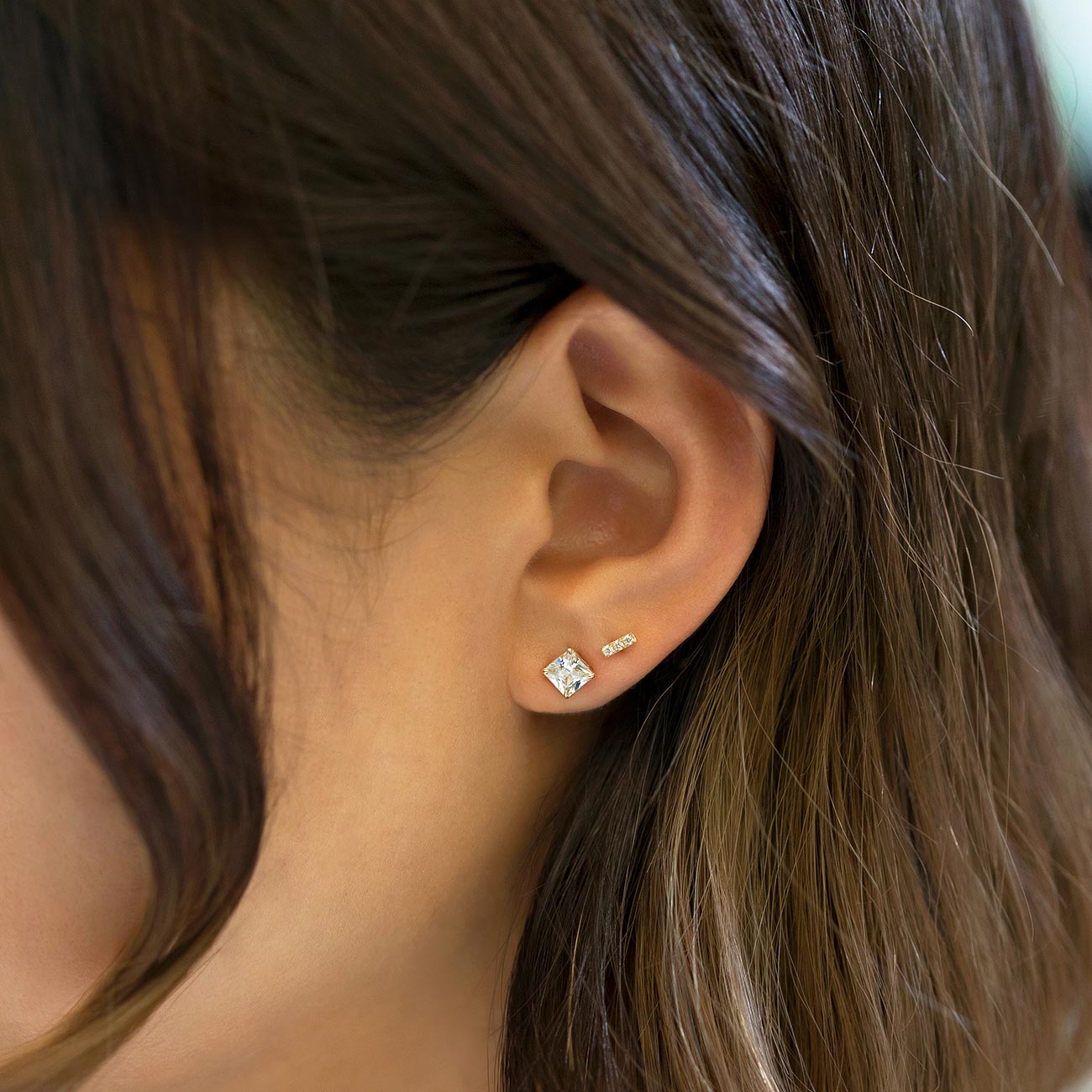 14K gold square pavé stud with white zirconia shown on a model's lobe