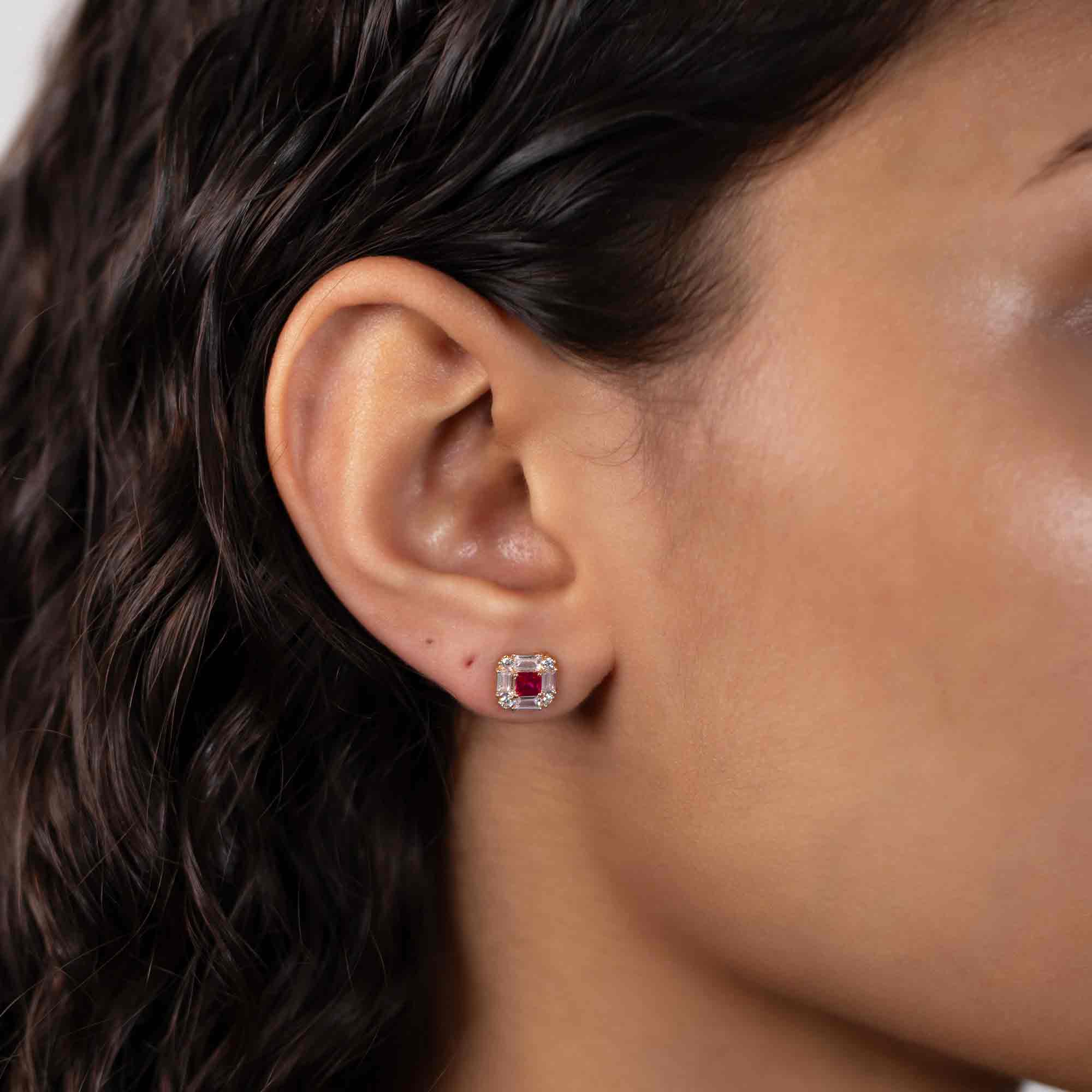 14K gold deco stud with a square ruby center and clear baguette and round stones, shown on a model's ear