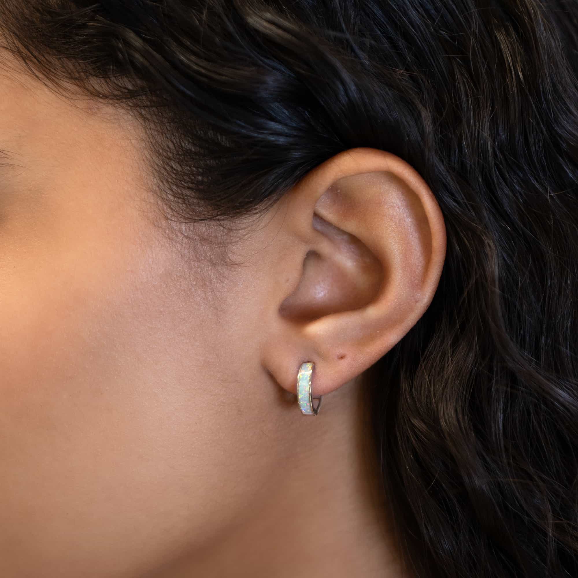14K white gold white opal huggie hoop shown close-up on a model's lobe