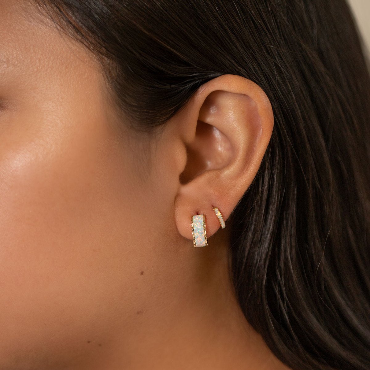 14K gold white opal chunky huggie hoop shown on a model's lobe with a thin ear cuff