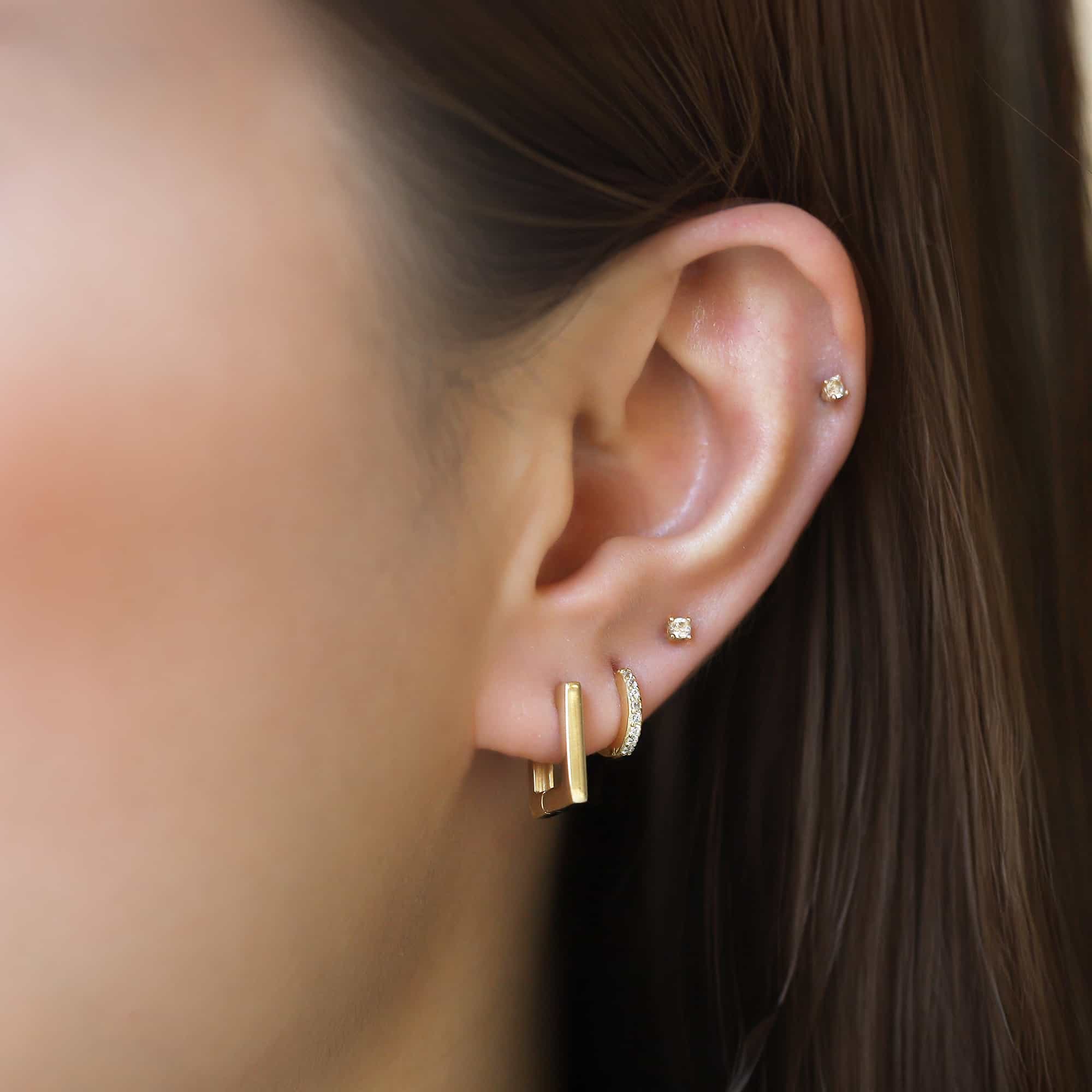 14K gold square huggie earring shown on a model's lobe, close-up side view