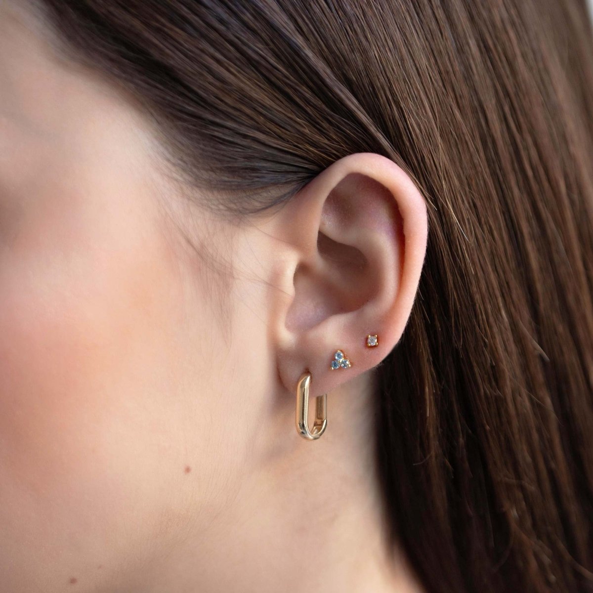 Close up of woman's ear featuring Gold Vermeil Birthstone Studs Set Aquamarine and chunky rectangular earring 