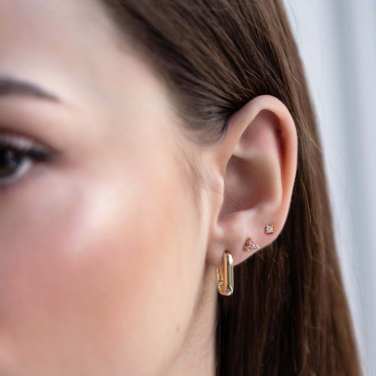 Close up of woman's ear featuring Gold Vermeil Birthstone Studs Set Pink and chunky rectangular earring 
