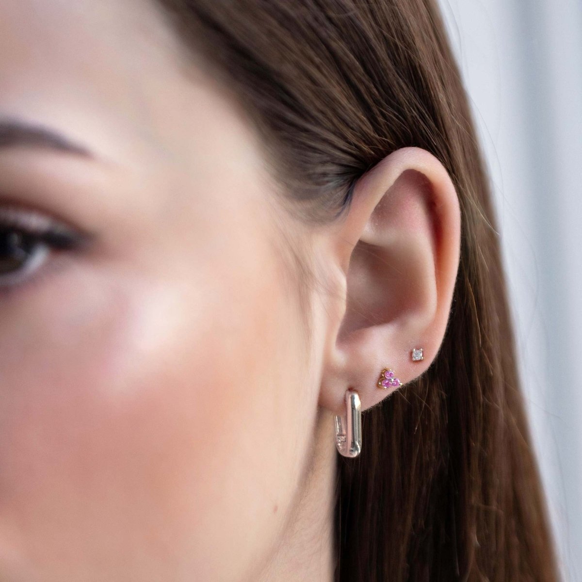 Close up of woman's ear featuring Sterling Silver Birthstone Studs Set Fuchsia Sapphire and chunky rectangular earring 