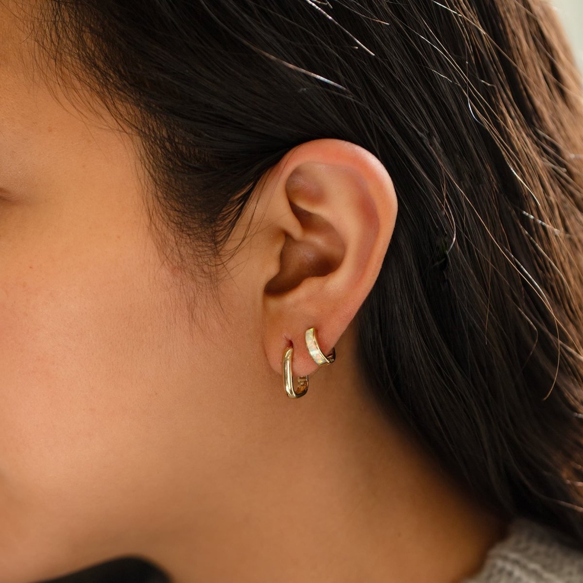 14K gold mini U-shaped hoop earrings, shown layered on a model's lobe