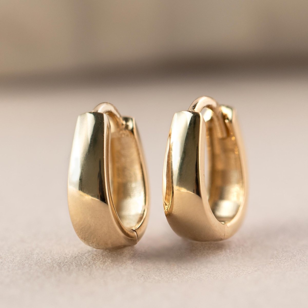 Gold vermeil chunky teardrop huggie hoops, close-up detail on a cream background