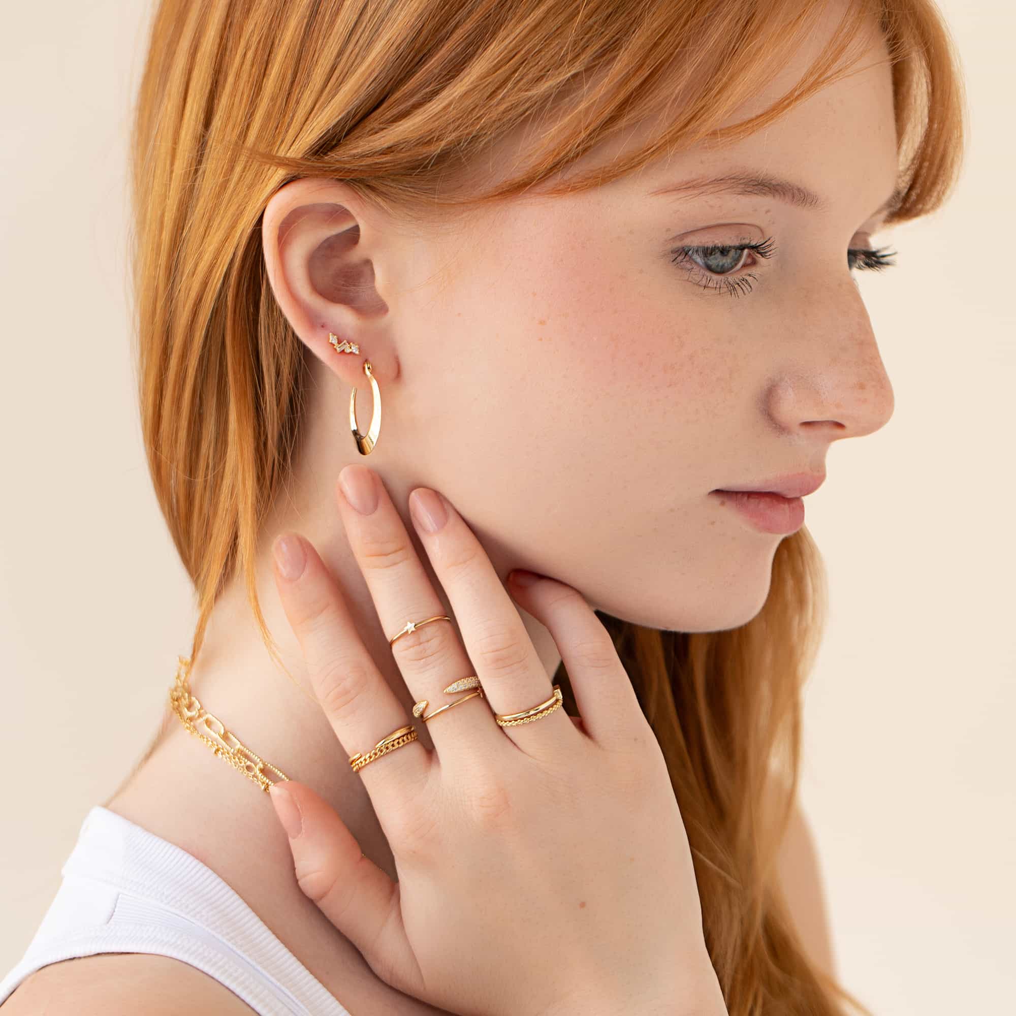 Stack of thin gold rings with pavé claw and clear-stone styles, shown on a model's hand
