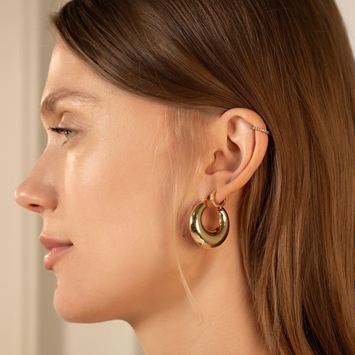 14K gold crescent bubble hoop earring shown on a model's lobe in profile