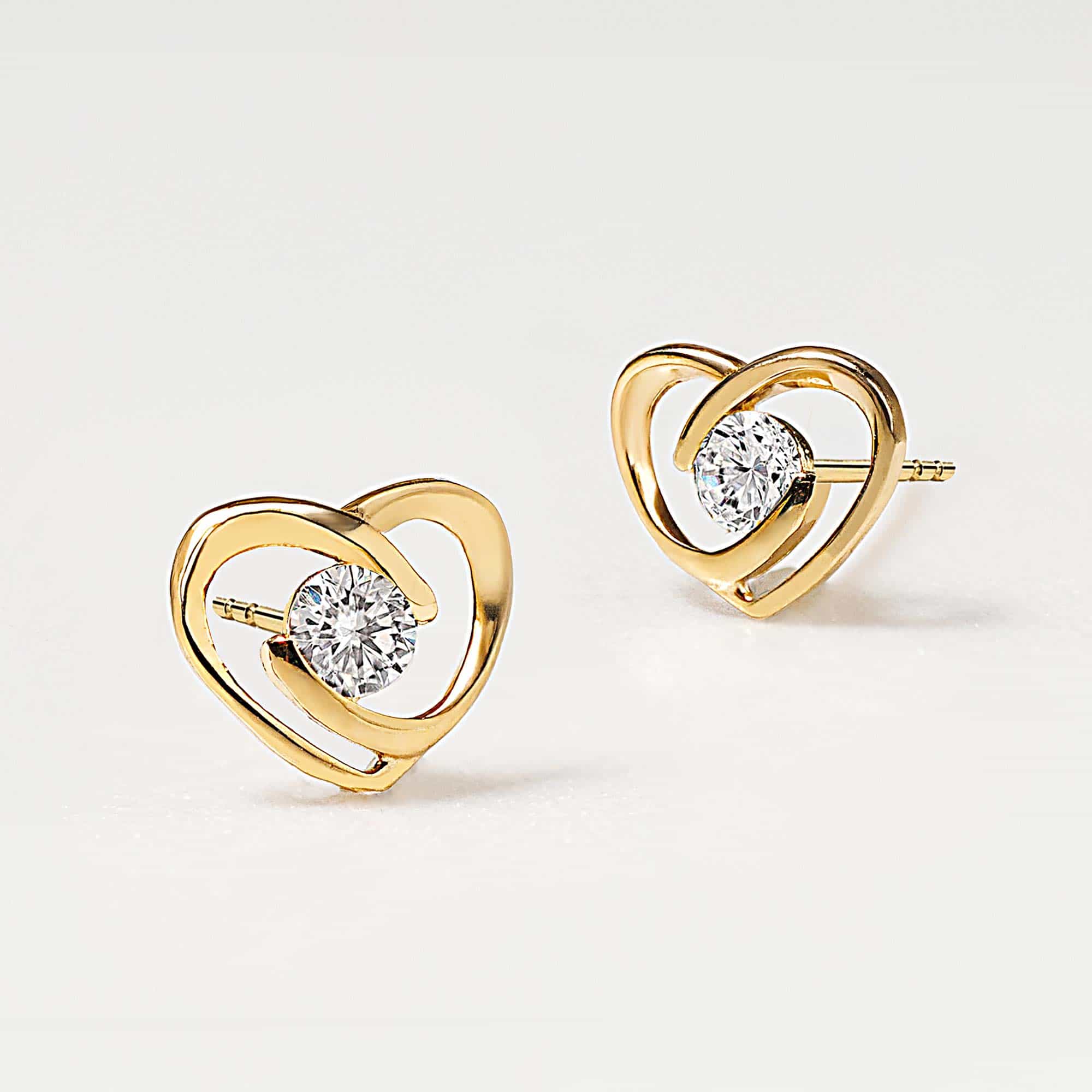 14K gold heart outline pavé studs with round clear white zirconia centers, angled on a white background