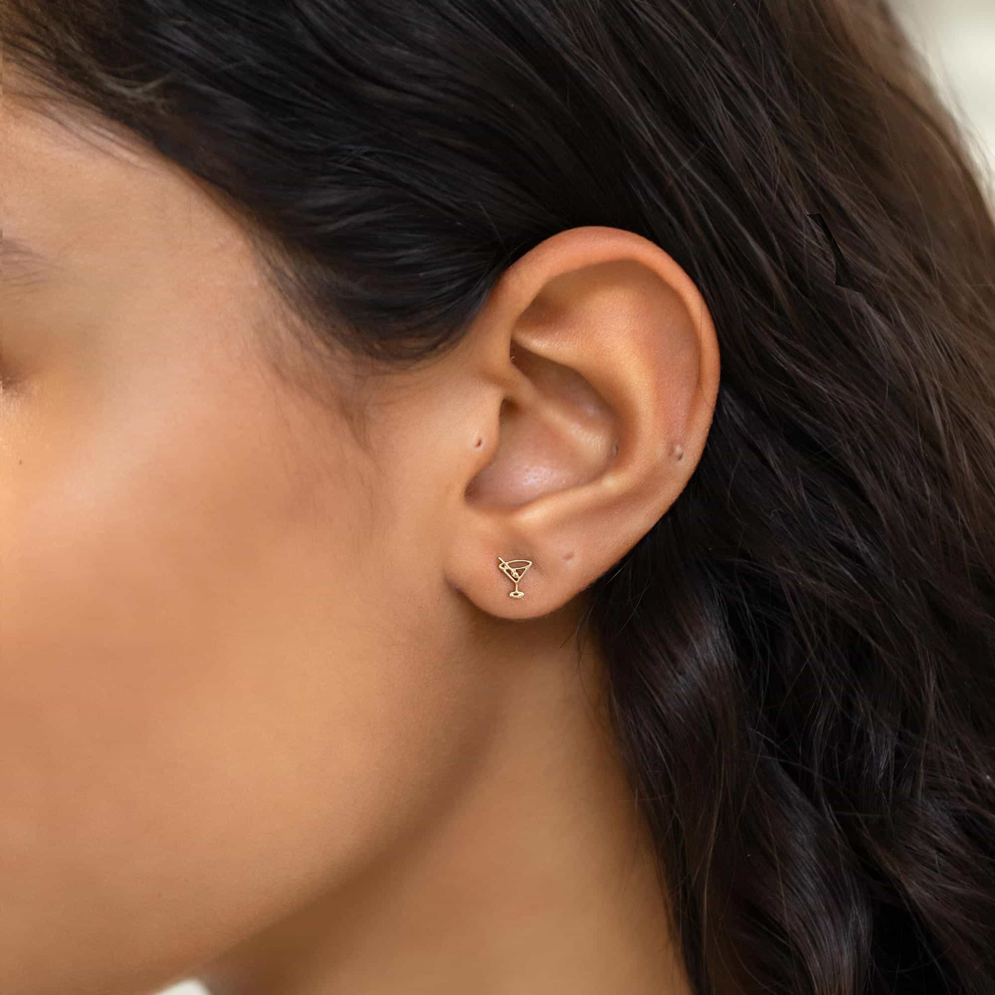 14K gold tiny martini glass stud shown on a model's lobe