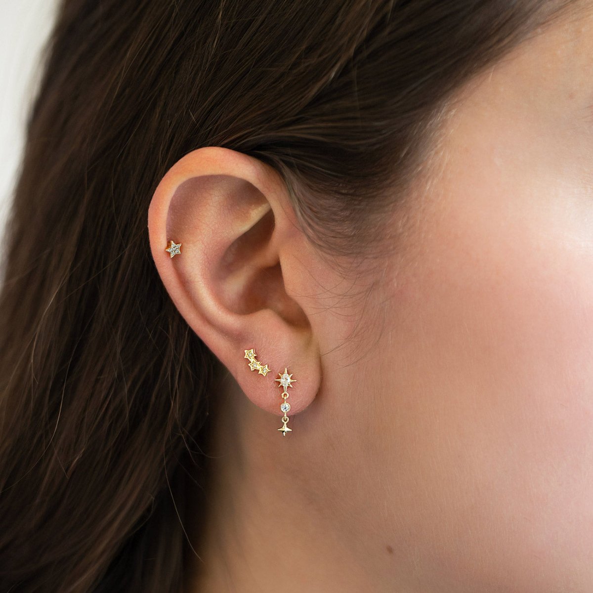 14K gold pavé star flat back stud with white zirconia, shown in a model's helix and lobe stack