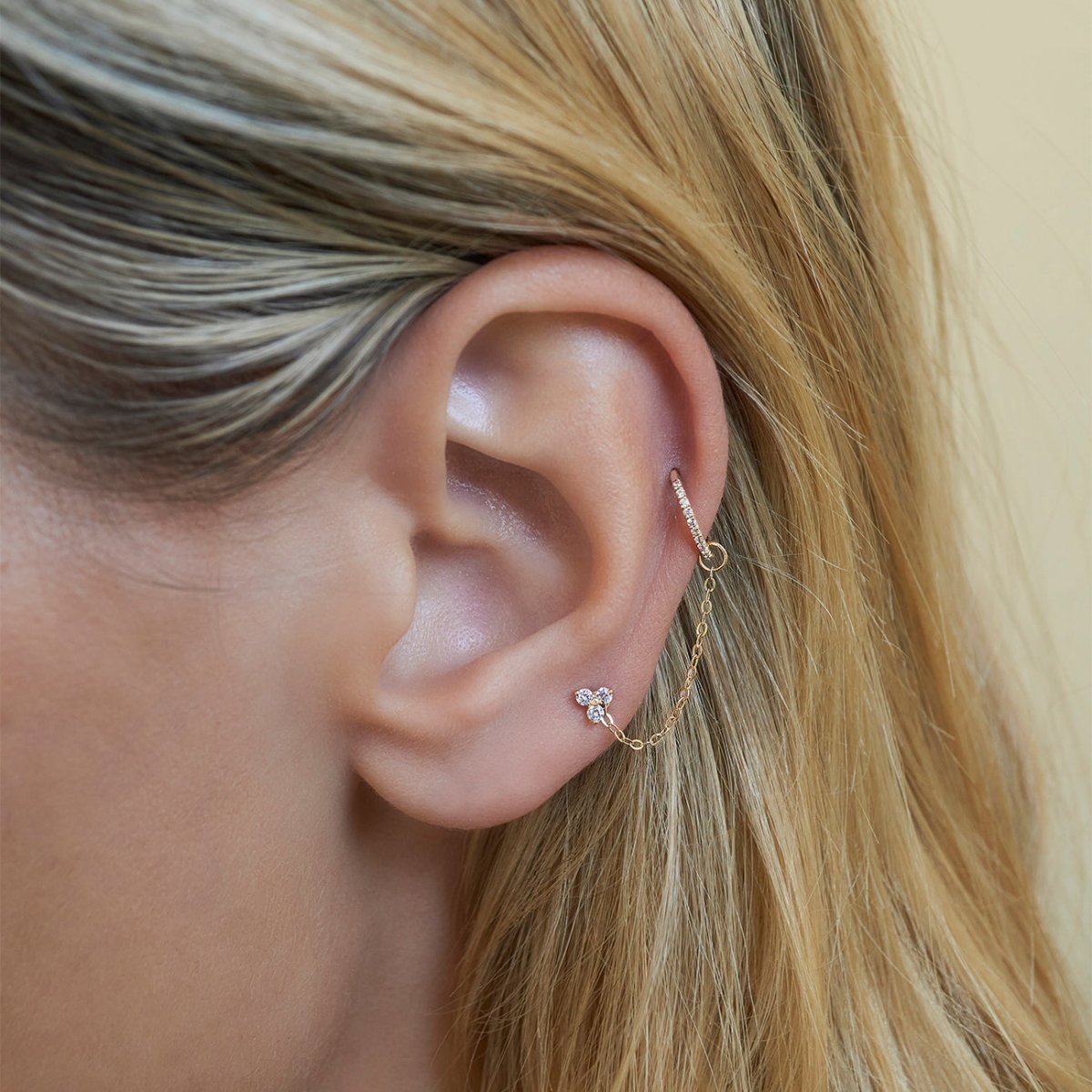 Close up of woman's ear featuring 14K Gold Tiny Clover Pave Stud and cartilage earring 