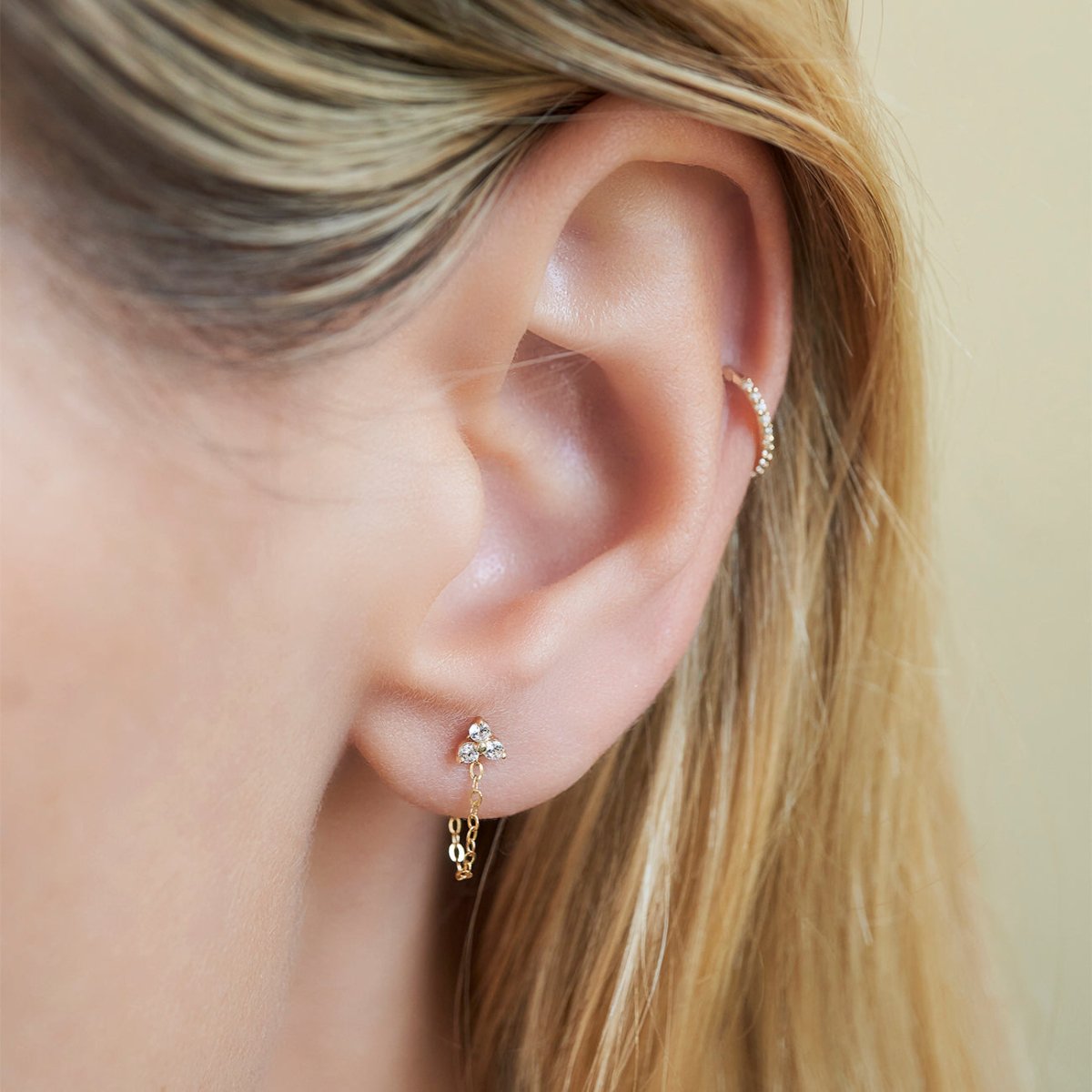 Close up of woman's ear featuring 14K Gold Tiny Gold Clover Stud Earrings and cartilage earring 
