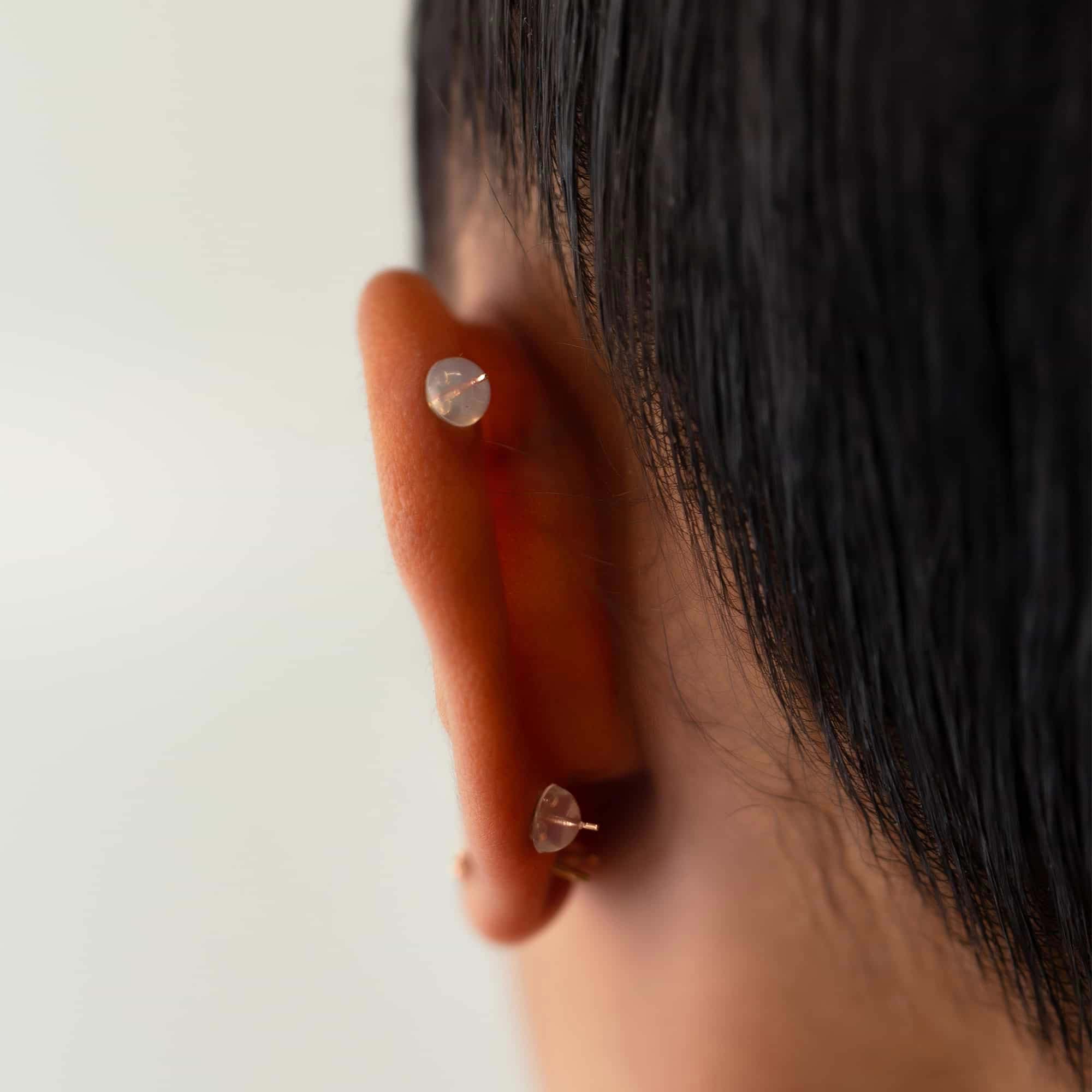Clear silicone earring back with a 14K rose gold core securing a stud, shown on a model's lobe