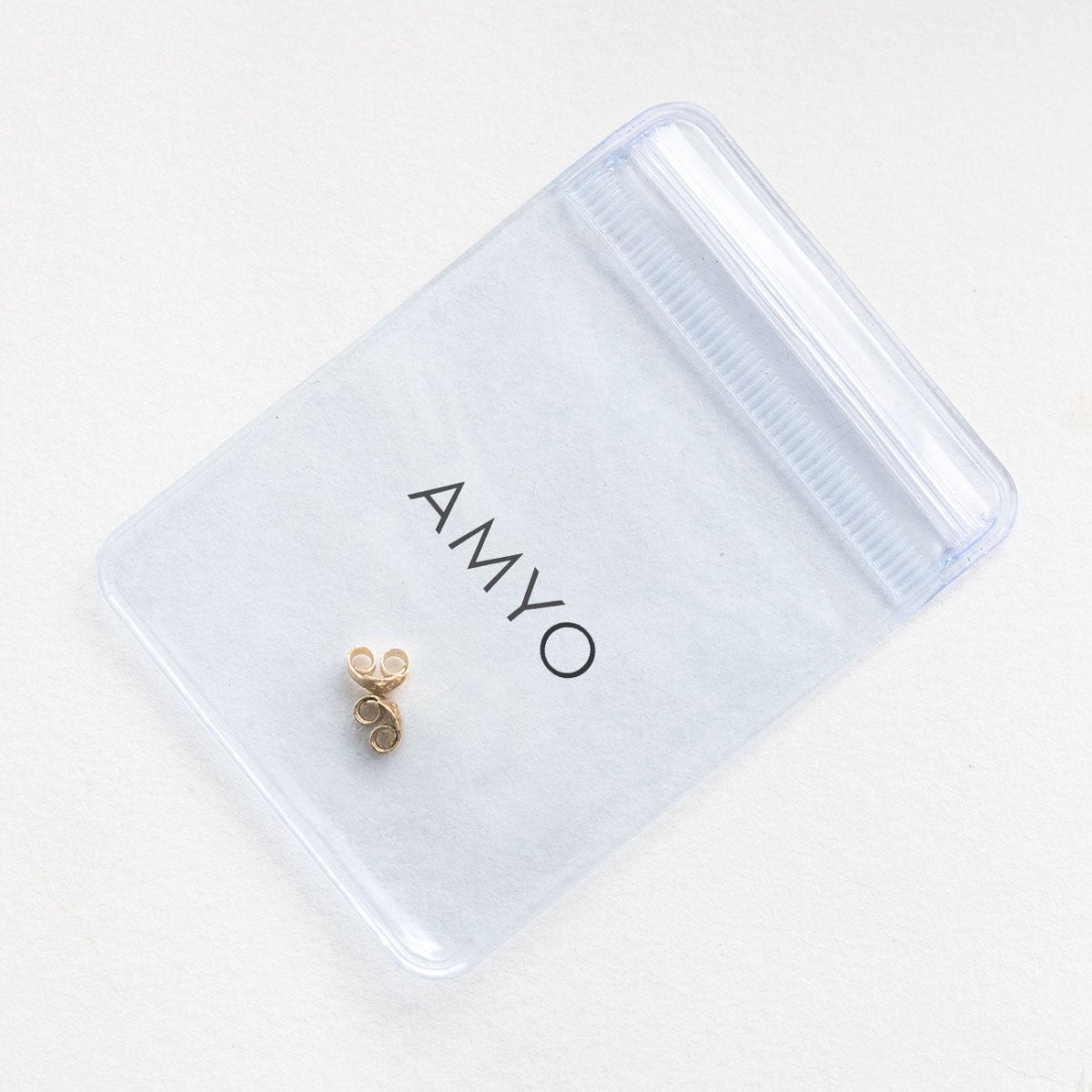 14K gold earring backs on a frosted AMYO pouch, close-up of a pair of friction butterfly backs
