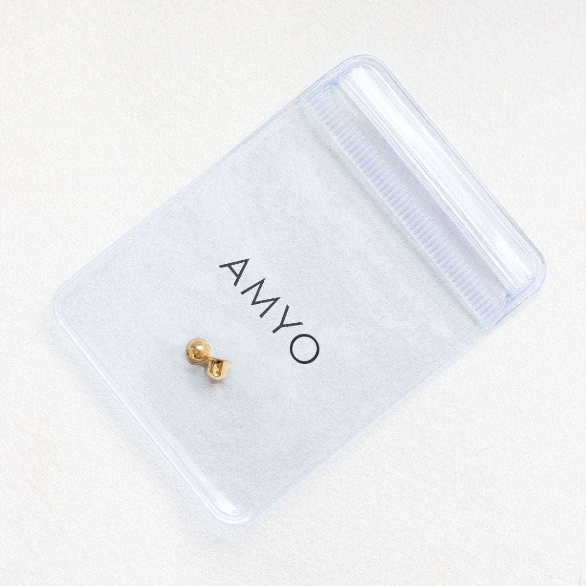 14K gold screw-back earring back in an AMYO pouch, on a cream background
