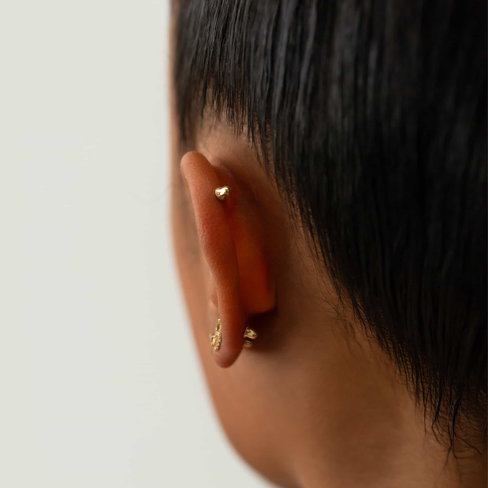 14K gold screw-back earring backs shown securing studs on a model's ear, close-up