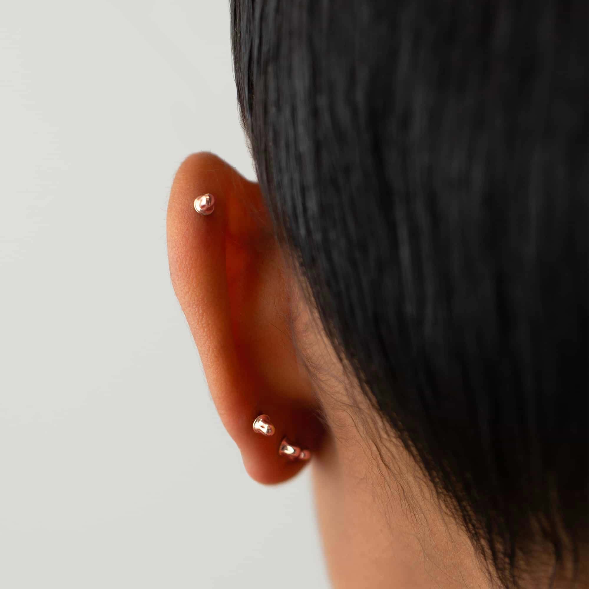 14K rose gold screw-back earring backs shown on a model's lobe and helix
