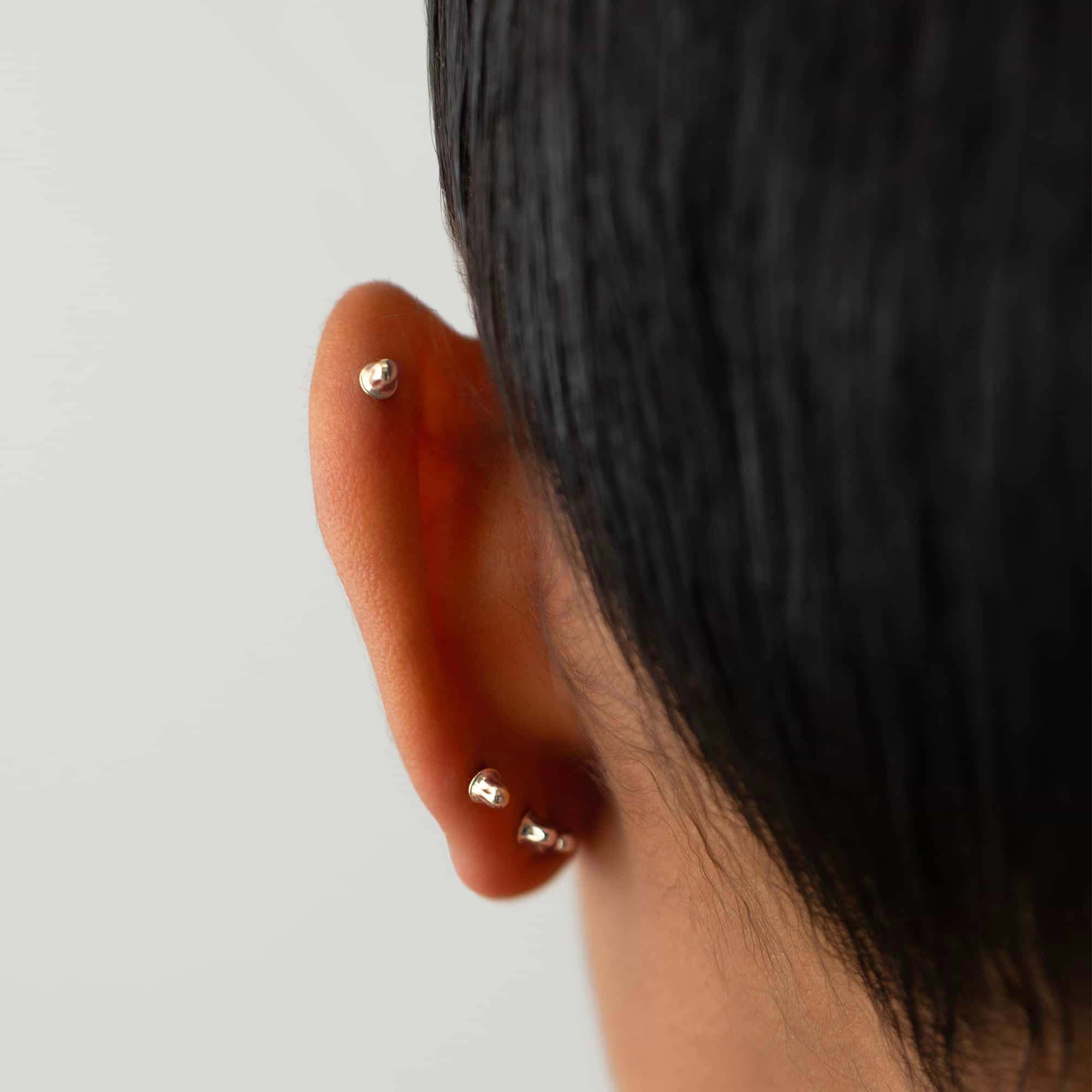 14K white gold screw-back earring backs shown on a model's lobe and helix, close-up