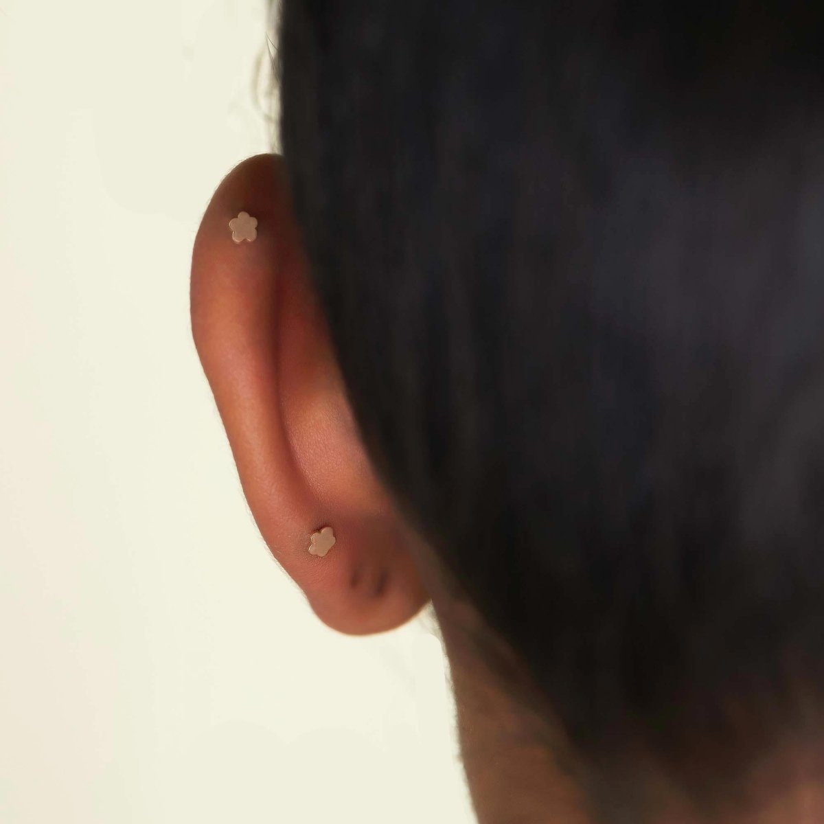 14K gold emerald flat back stud worn in the lobe, shown in a styled ear stack on a model
