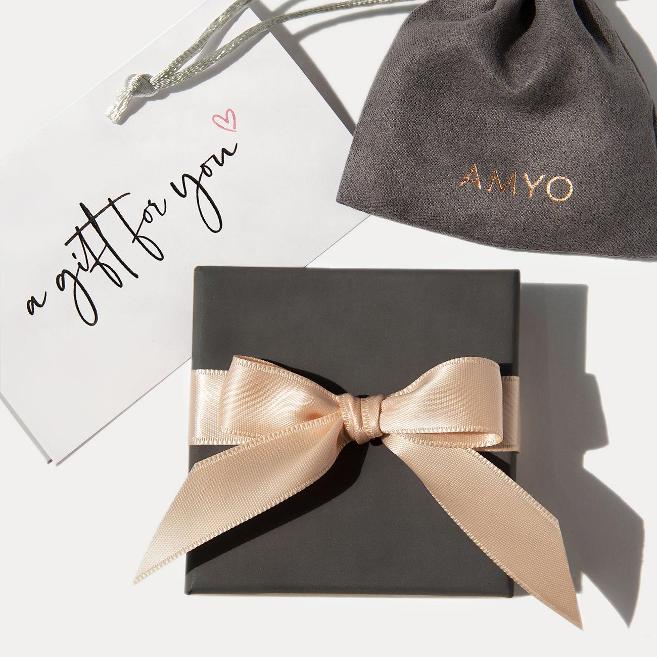 AMYO gift packaging with gray box, blush ribbon, logo pouch, and a gift card