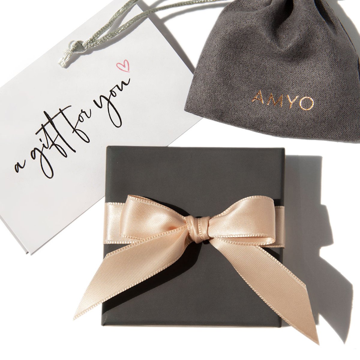 Gray ribbon-tied gift box with a pouch and a folded gift card, on a white background