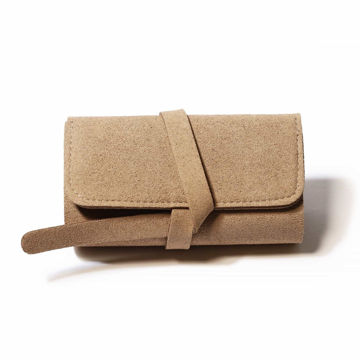 Tan suede travel jewelry roll closed with a wraparound tie, on a white background