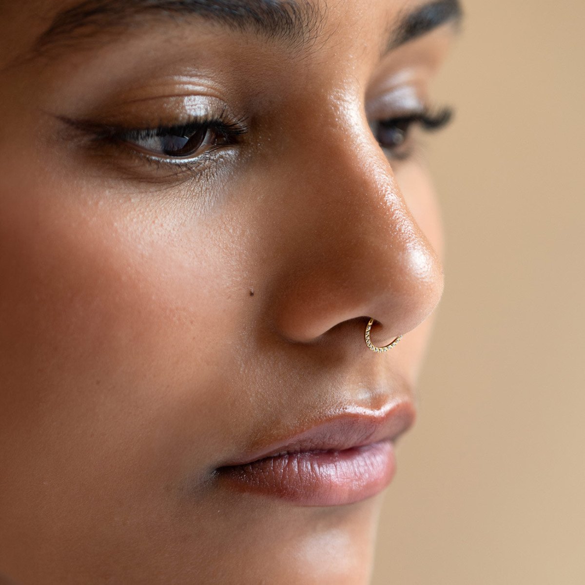 Titanium seamless nose hoop with front pavé crystals, shown on a model.