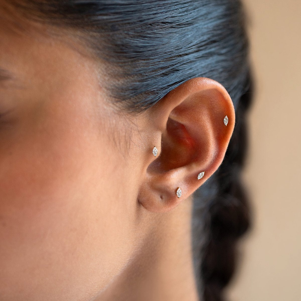 Gold flat back stud earrings with marquise-shaped crystals, shown on a model's ear | #Gemstone_White Zirconia