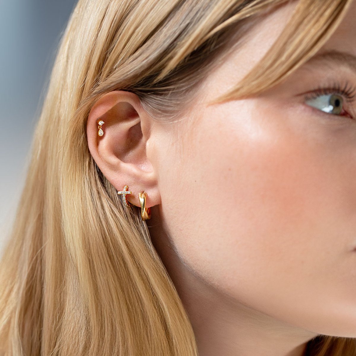 Gold vermeil pear-shaped zirconia dangle flat back stud shown in a styled ear stack on a model