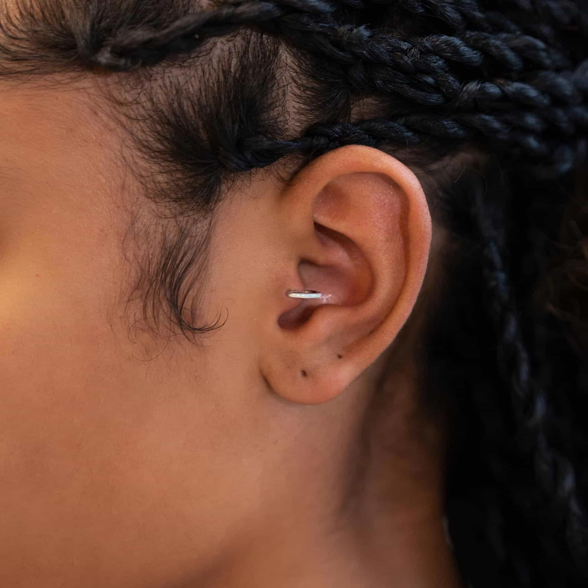 Sterling silver seamless clicker hoop with opal inlay, shown on a model's helix piercing