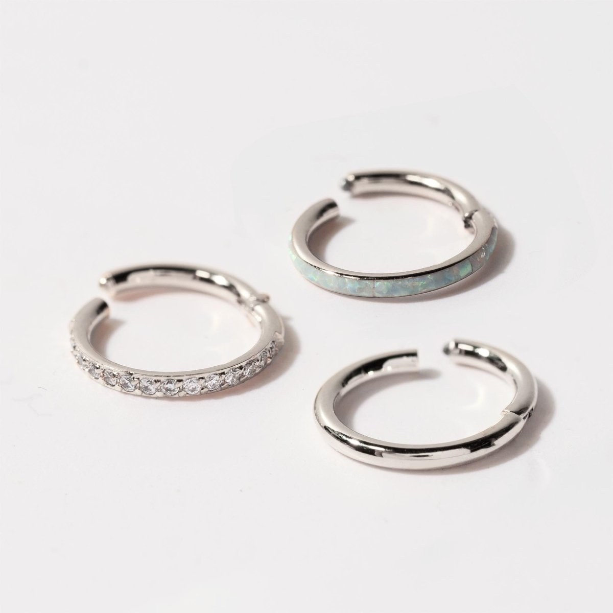Three sterling silver clicker hoops with pavé, white opal inlay and plain finishes, on a white background