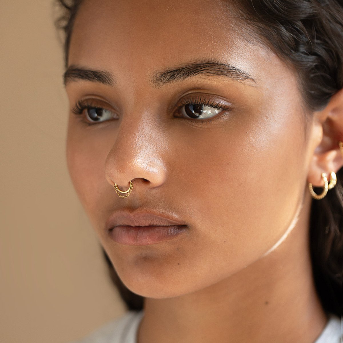 Gold titanium seamless clicker chain hoop worn as a nose ring on a model