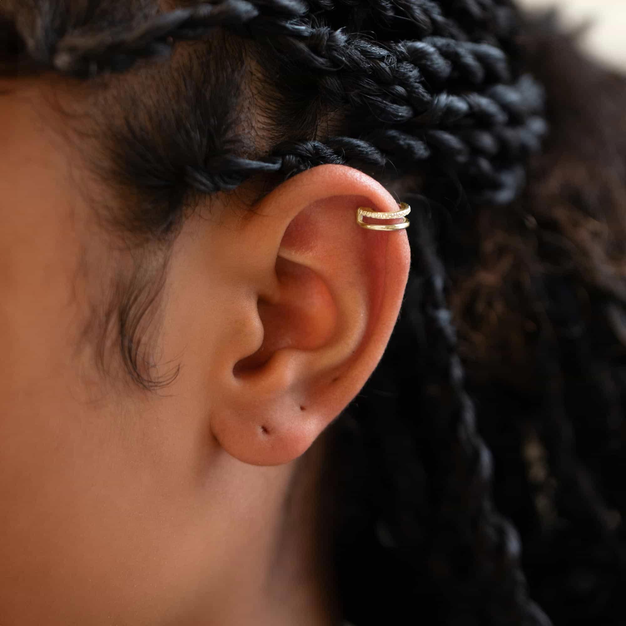 Gold titanium pavé double-hoop cartilage earring with white zirconia, shown on a model's helix