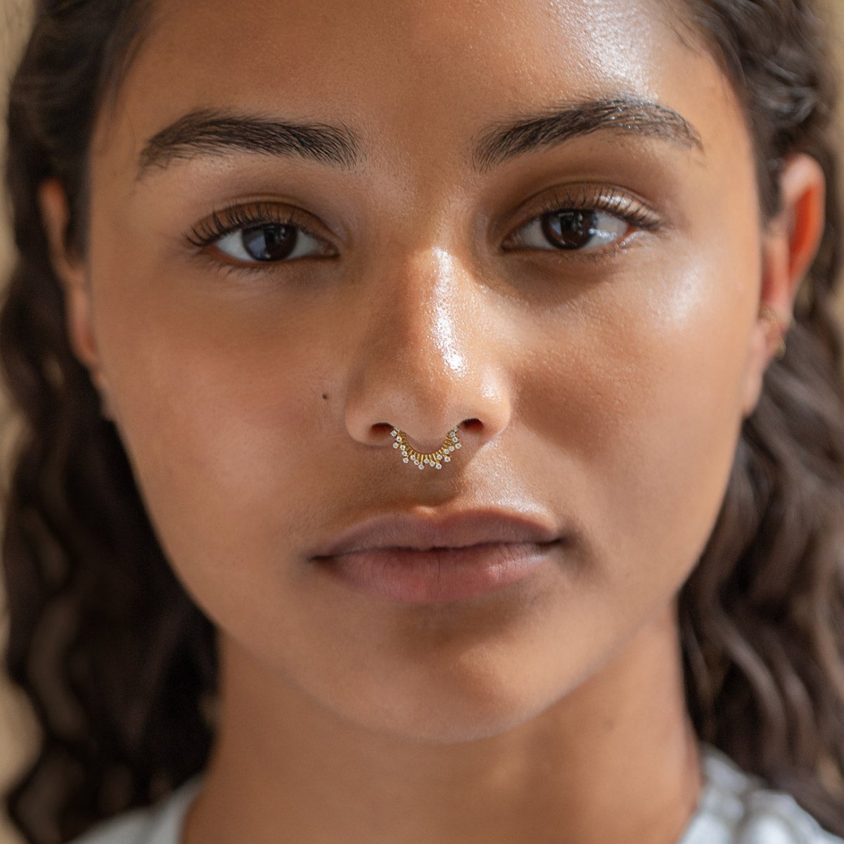 Gold titanium pave deco seamless hoop with white zirconia worn as a septum ring, shown on a model