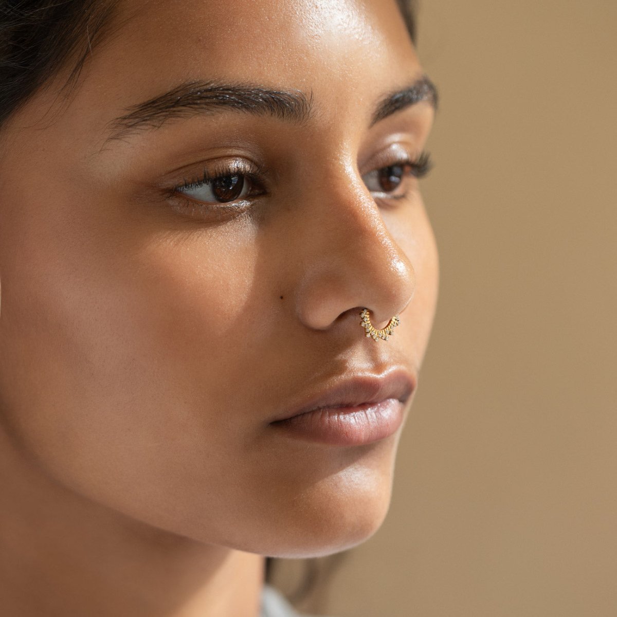 Gold titanium pave white zirconia septum hoop, shown on a model in profile