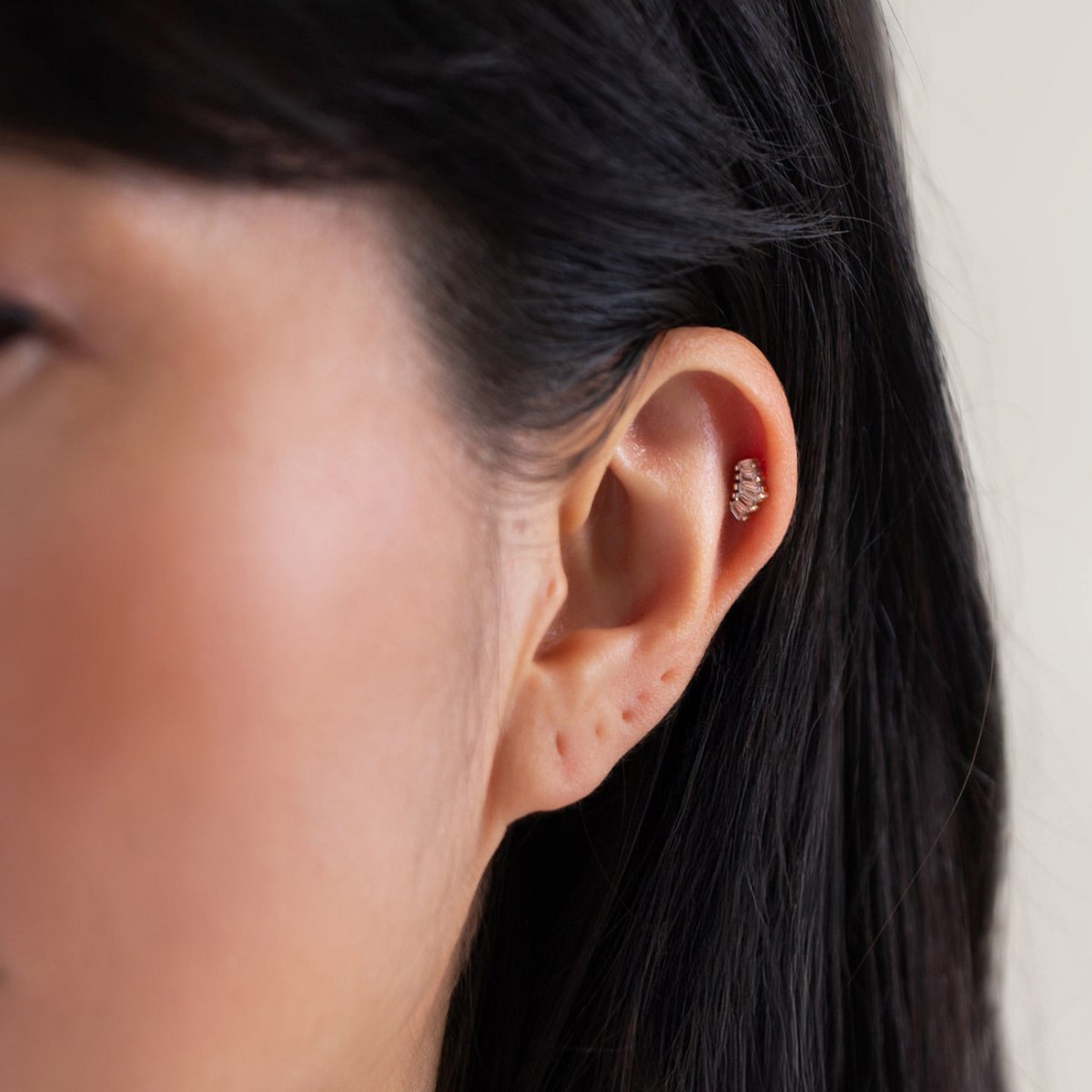 Sterling silver baguette flat back stud shown in a helix piercing, close-up on a model's ear