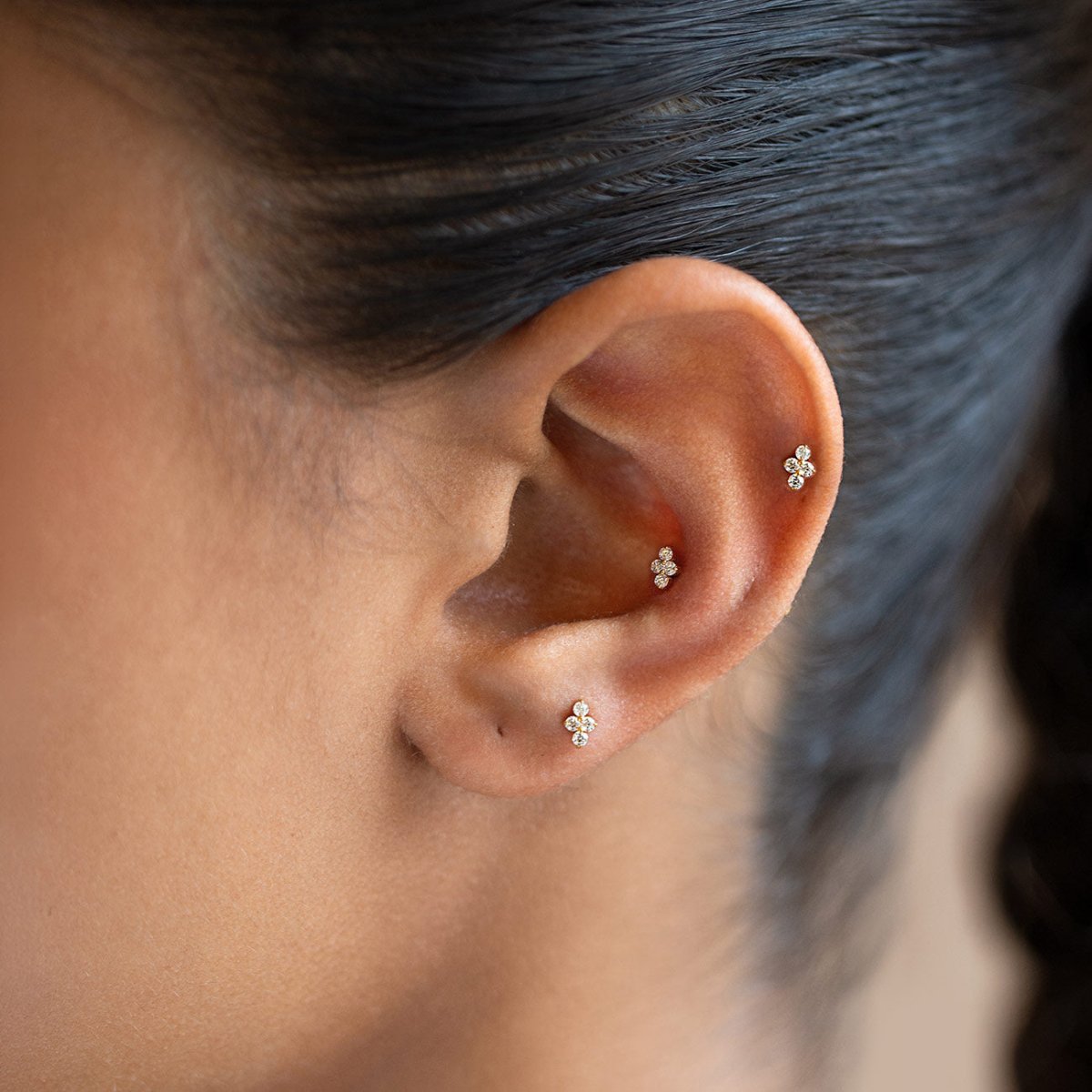 Gold Titanium flat back stud earrings with four round crystals, shown on a model's ear.