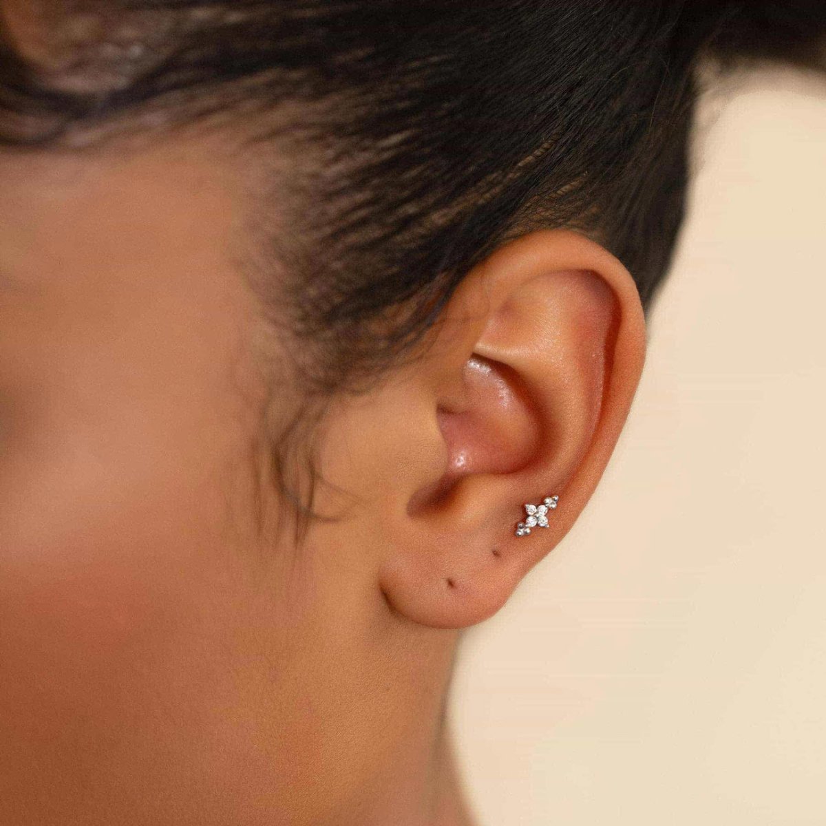 Sterling silver zirconia flower cluster flat back stud shown on a model's upper ear cartilage