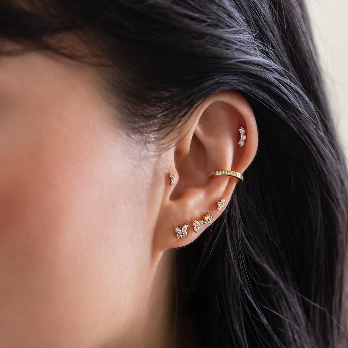 Gold flat back studs and ear cuff with clear cluster and butterfly stones, styled in a model's ear stack