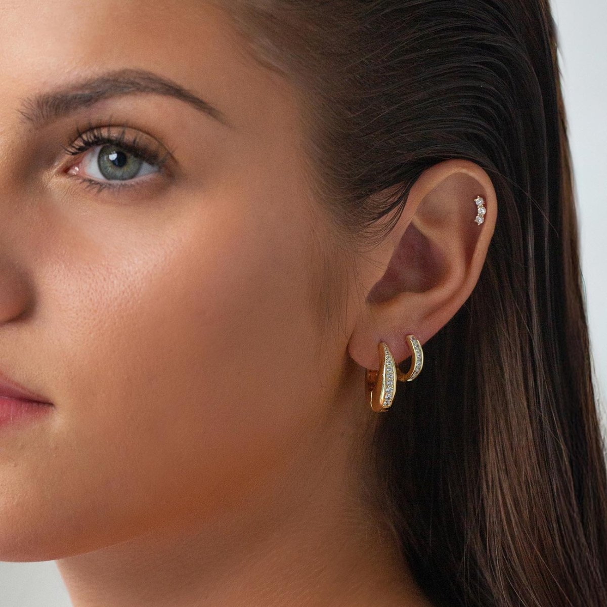 Gold vermeil chunky huggie hoop with a pavé zirconia inlay, shown on a model's lobe with stacked studs