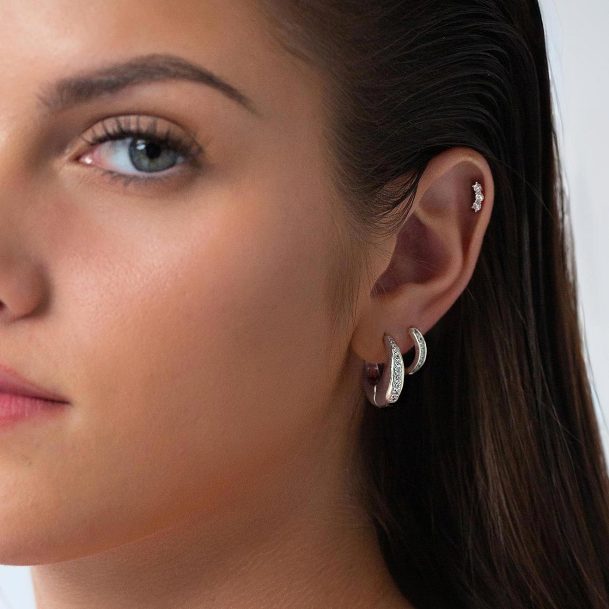 Sterling silver chunky huggie hoop with a pavé zirconia inlay, shown on a model's lobe with a stud