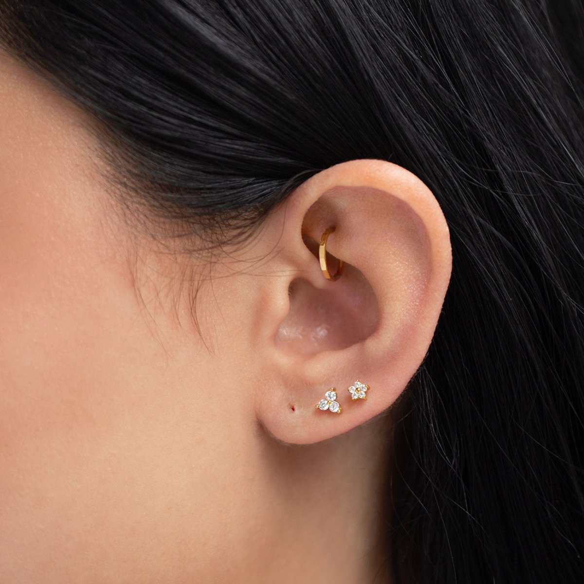 Gold titanium faceted clicker hoop worn in a helix piercing, shown on a model's ear