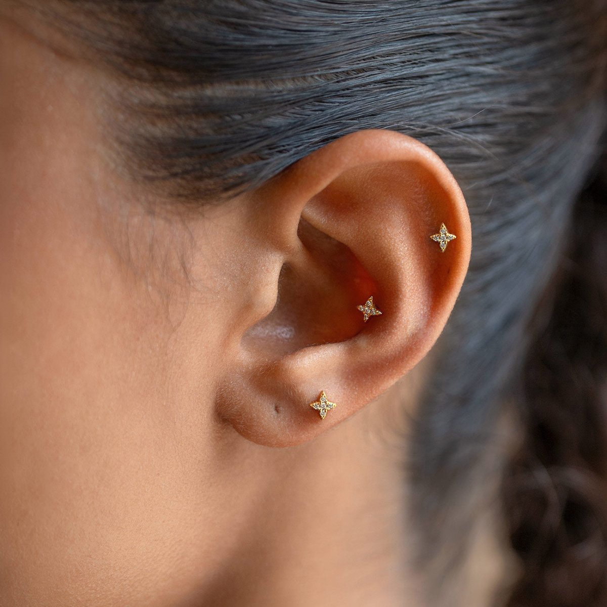 Gold Vermeil flat back stud earrings with four-point star-shaped crystals, shown on a model's ear.