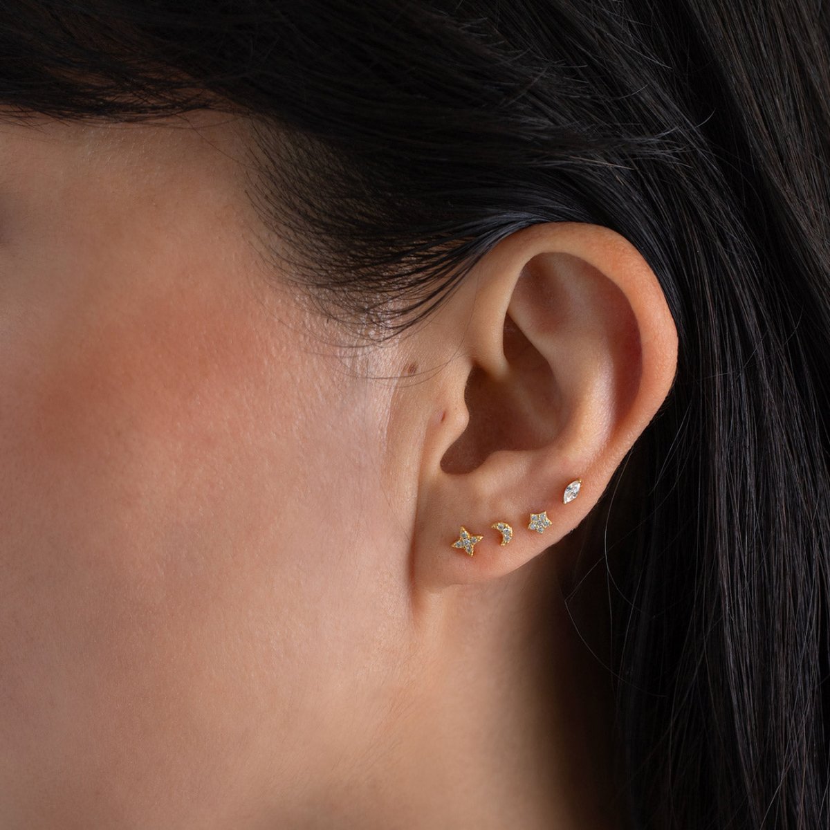 Gold moon and star flat back studs with clear stones, styled in a model's lobe stack